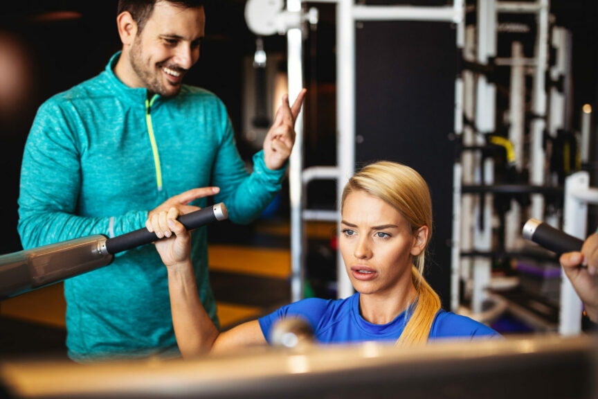 Woman with her personal fitness trainer in the gym exercising
